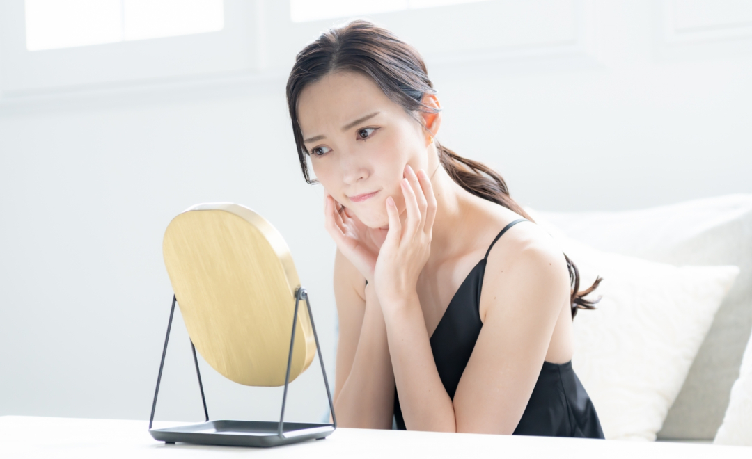 ニキビを気にして鏡を覗き込む女性