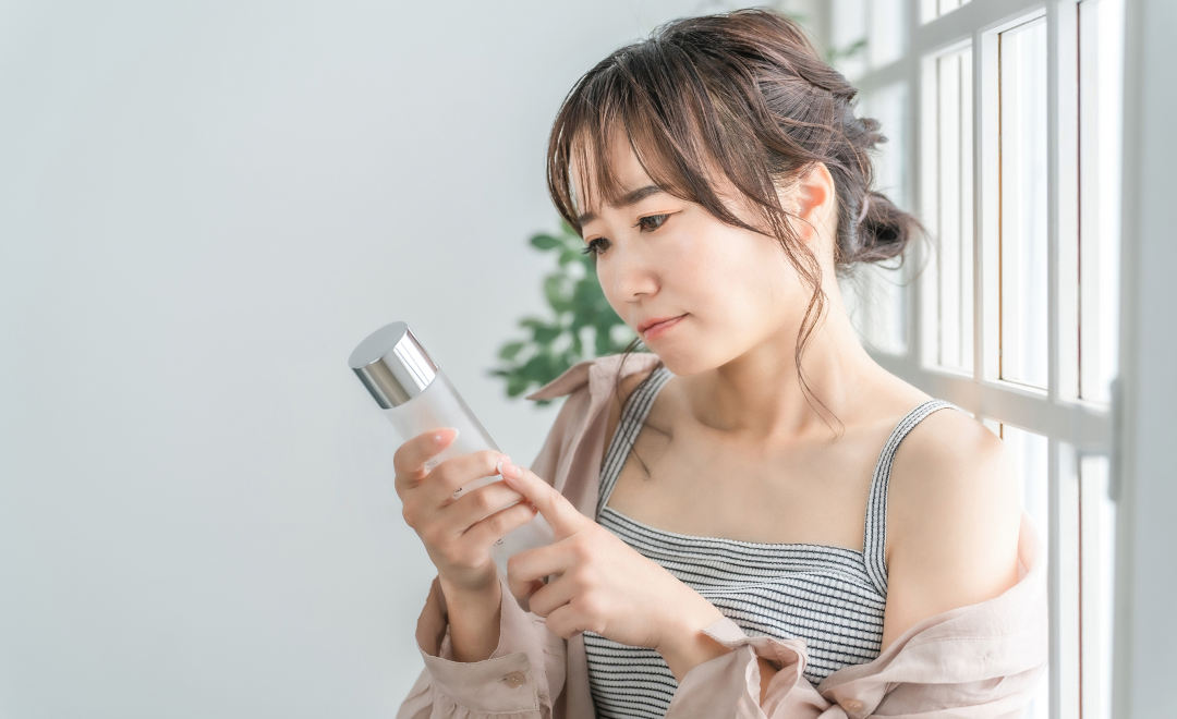 化粧水を見て悩む女性